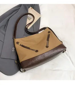 Detail of khaki canvas bucket bag with dark brown leather trim and diagonal zipper