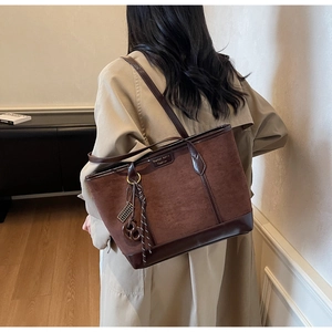 Dettaglio della borsa tote marrone scuro in pelle scamosciata opaca e lucida con ciondoli