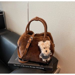 Detailansicht der braunen flauschigen Plüschtasche mit Ledergriff und Bärenanhänger