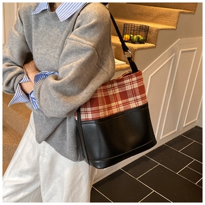 Detail of plaid tweed and black leather patchwork tote bag on a model's shoulder