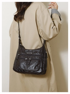 Close-up of soft brown leather crossbody bag featuring multiple zipper compartments