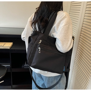 Détail du sac en nylon noir avec plusieurs poches zippées à l'avant et poche latérale