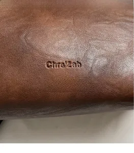 Macro shot of the brown leather shoulder bag featuring a debossed Chrs'2ab brand logo