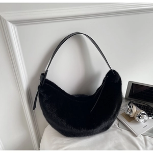 Close-up of black fuzzy moon bag on a clean white background with minimalist props
