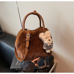 Detail der braunen Plüschtasche mit Ledergriff und süßem Teddybär-Anhänger als Akzent