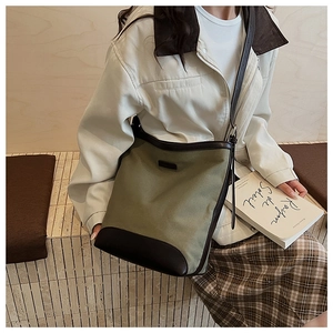 Detail of army green canvas bucket bag with brown leather trim worn by model