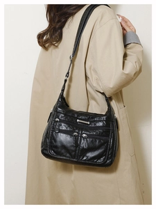 Close-up detail of soft black PU leather texture and multiple zipper pockets on tote bag