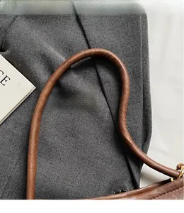 Detail of round brown leather shoulder strap and gold hardware on retro handbag