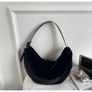 Close-up of fluffy black faux fur half-moon bag with adjustable leather strap