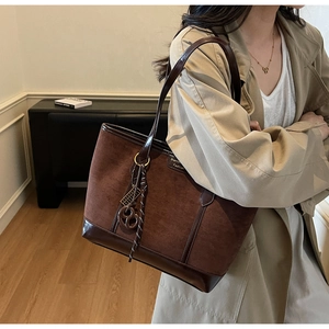 Dettaglio della borsa tote in pelle scamosciata caffè e pelle marrone con ciondolo