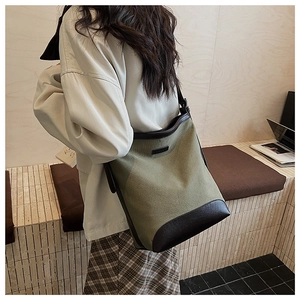 Detail of army green canvas and brown leather bucket bag shown on person back