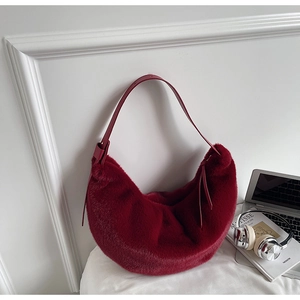 Close-up of deep red faux fur crescent bag with soft texture and leather strap detail