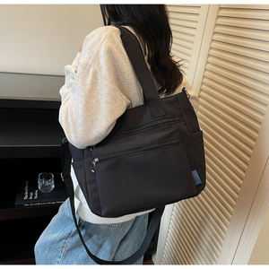 Détail du sac bandoulière en nylon noir avec design multi-poches et large sangle réglable