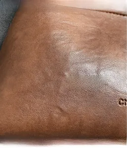 Detail of brown leather texture with litchi grain and embossed lettering on shoulder bag