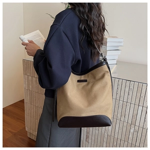 Detail of khaki canvas and brown leather shoulder bag shown from a stylish side view angle