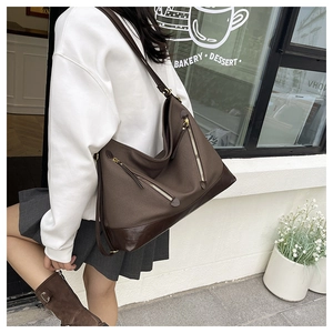 Detail of canvas and leather bucket bag featuring metal zipper pockets for daily commute
