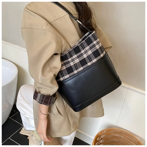 Detail of checkered fabric and black matte PU leather stitching on a bucket shoulder bag