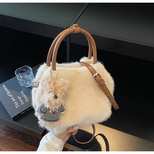 Detail der Plüschhandtasche aus cremefarbenem Kunstpelz mit braunem Ledergriff