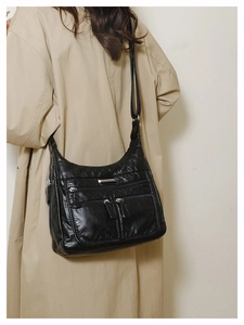 Detail of black soft leather crossbody bag with multiple zip pockets and silver hardware