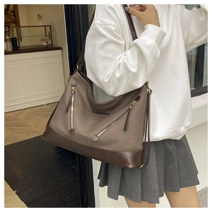 Detail showing high-capacity canvas and brown leather bucket bag with gold zippers