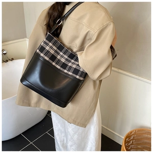 Close-up of black and white checkered bucket bag with leather strap and silver buckle