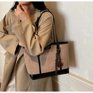 Dettaglio della borsa tote in pelle e scamosciato con ciondolo intrecciato e anelli metallici