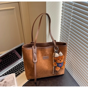 Detailed texture of brown matte leather tote bag with cute bear charm and long straps