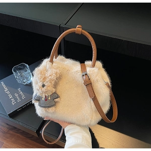 Detail der flauschigen cremefarbenen Handtasche mit braunen Griffen und Bärenanhänger
