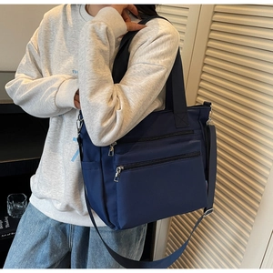 Détail du sac fourre-tout en nylon bleu marine avec poches zippées et bandoulière réglable