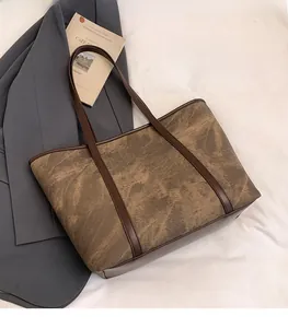 Detail of vintage brown marbled texture tote bag with leather straps on white fabric