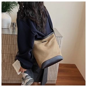 Detailed back view of khaki canvas bucket bag with dark brown leather trim on a model