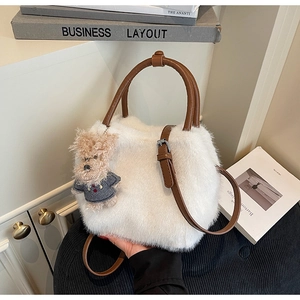 Detail der weißen Plüschhandtasche mit braunen Ledergriffen und einem süßen Bärenanhänger