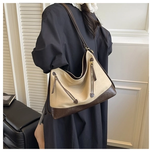 Detailed view of a beige canvas tote bag with dark brown leather straps on a model
