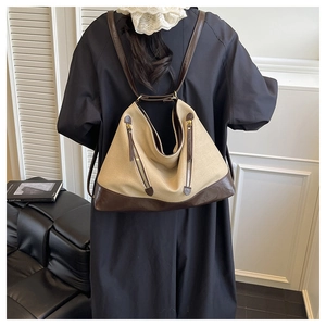 Detail of off-white canvas and brown leather bucket bag with gold zipper accents