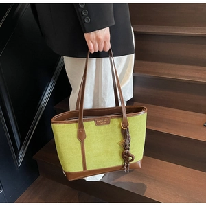 Borsa tote in pelle scamosciata verde con manici marroni portata su scale in legno