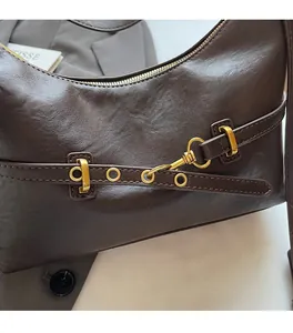 Dettaglio borsa sottobraccio in pelle marrone scuro con fibbia in metallo vintage