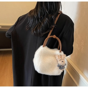 Rückansicht einer weißen Kunstfelltasche mit braunen Lederriemen und Bärenanhänger