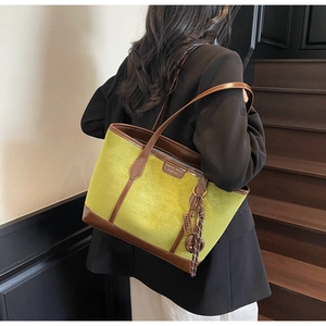 Detail view of large olive green suede tote bag with brown leather trim and metal logo