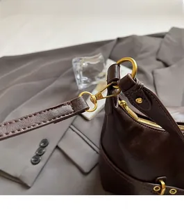 Dettaglio della pelle marrone e degli accessori metallici dorati sulla borsa a spalla