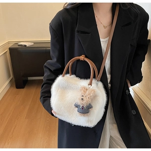 Detail der weißen Plüschtasche mit braunem Ledergriff und süßem Teddybär-Puppendekor