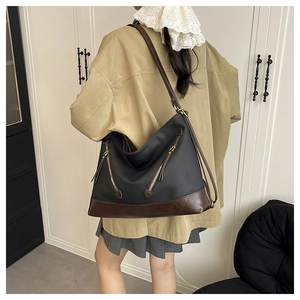 Detail of hobo bucket bag in black and brown contrast leather on model in a studio