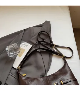 Dettaglio della tracolla regolabile e fibbia dorata sulla borsa tote vintage marrone