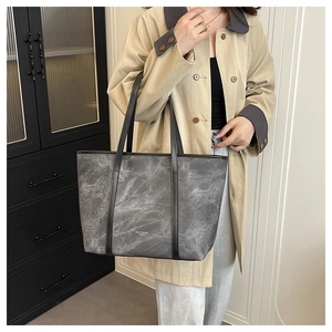 Detail of grey marble pattern tote bag with logo handle shown on fashion model