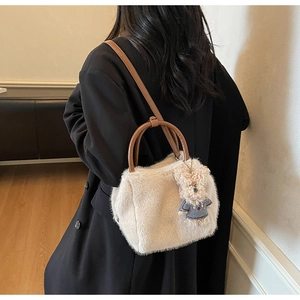 Detail der flauschigen cremeweißen Handtasche mit weichem Kunstfell und niedlichem Teddybären