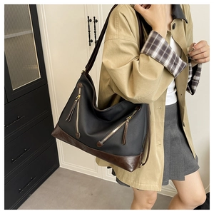 Hobo shoulder bag featuring black fabric, brown leather trim, and gold zipper details