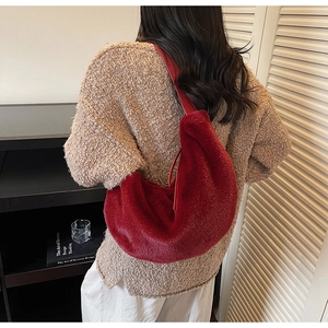 Detail view of red faux fur hobo bag with slim leather strap on a model's shoulder