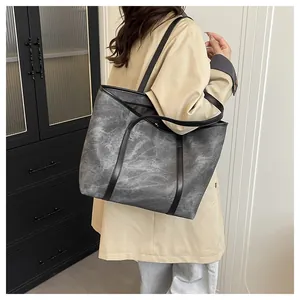 Detail of a large dark grey marble texture tote bag with black leather shoulder straps