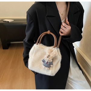 Plüschige cremefarbene Schultertasche mit braunem Lederriemen und blauem Bärenanhänger