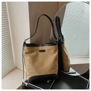 Detailed close-up of khaki canvas and brown leather stitching on a stylish bucket bag