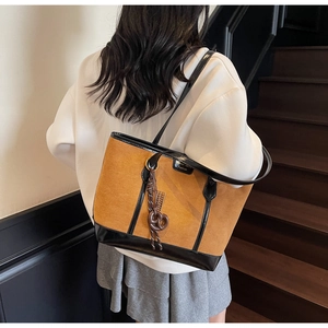 Dettaglio di una grande borsa tote in pelle scamosciata marrone con manici in vernice nera